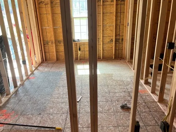Wood-stud framed interior with rough-in outlet boxes and NM cable beside a bright window opening.